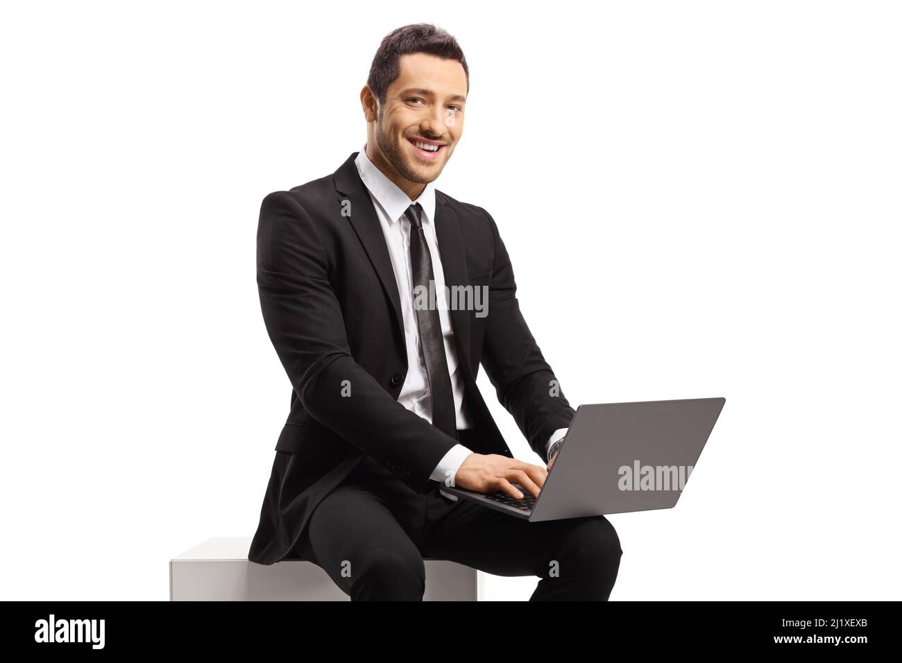 Homme d'affaires assis et utilisant un ordinateur portable, regardant la caméra isolée sur fond blanc Banque D'Images