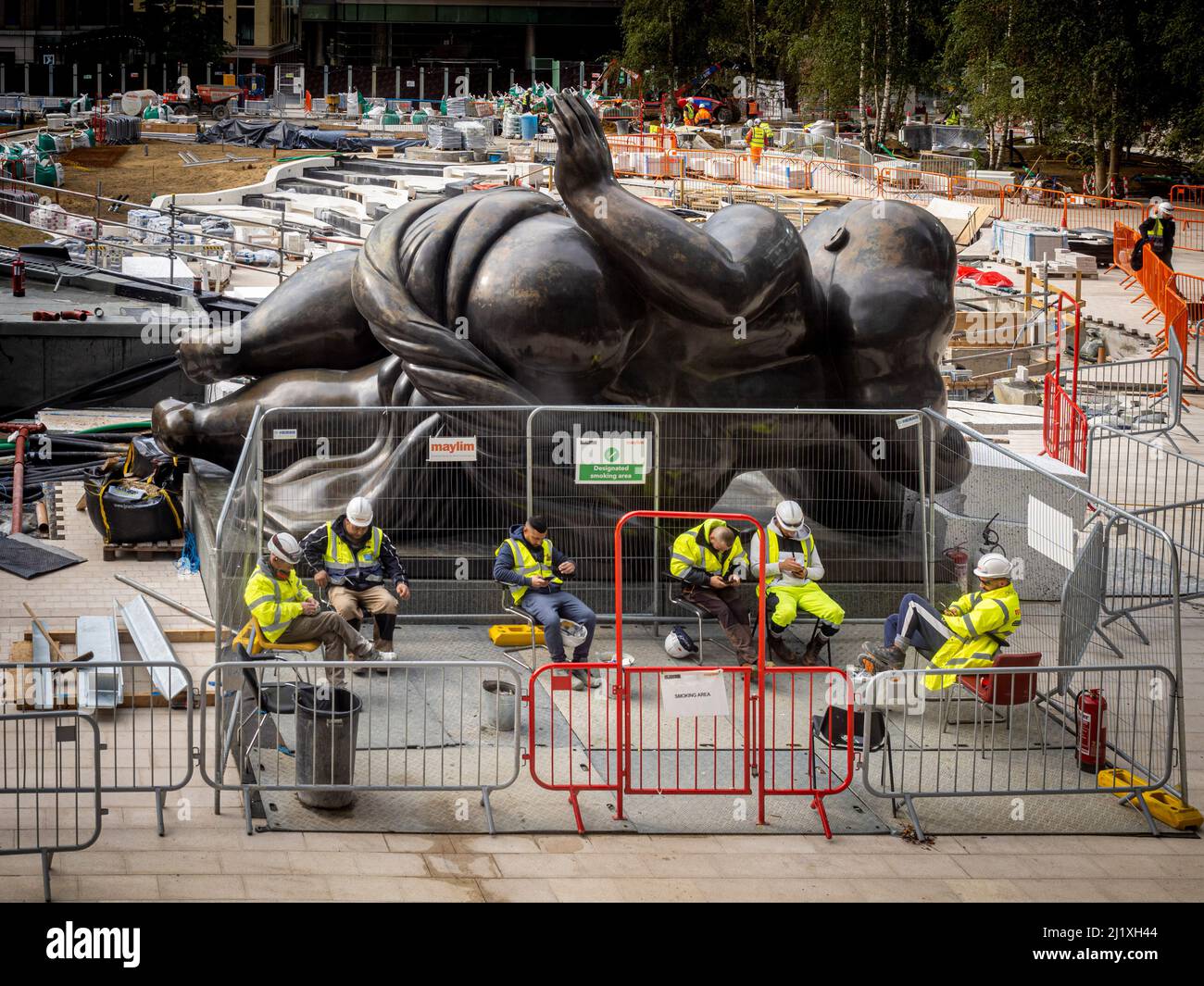 Des ouvriers de la construction caucasiens sont en pause dans un espace fumeur désigné sur la place des changes, avec la statue de Bondgate venus derrière. Londres. Banque D'Images