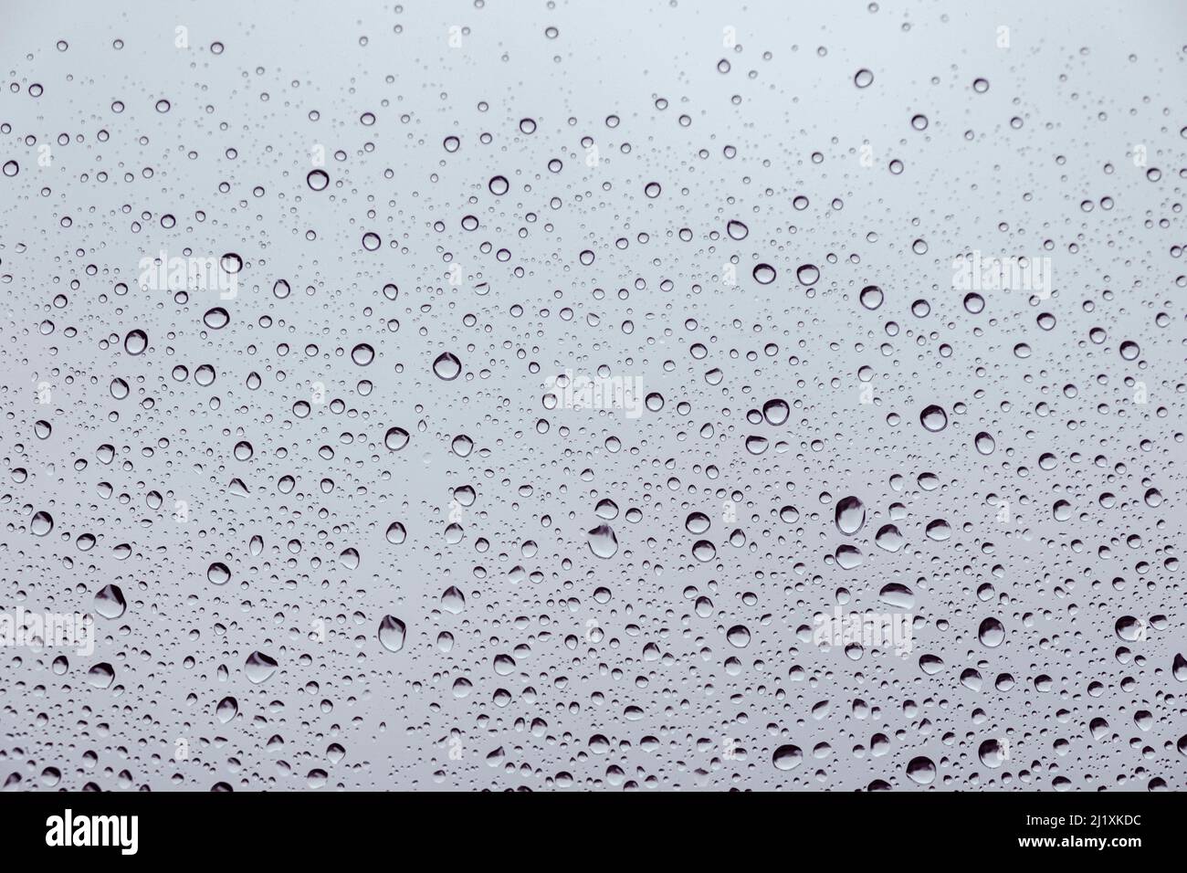 Gouttes de pluie sur une fenêtre avec des rivulets d'eau qui descendent le volet. Banque D'Images
