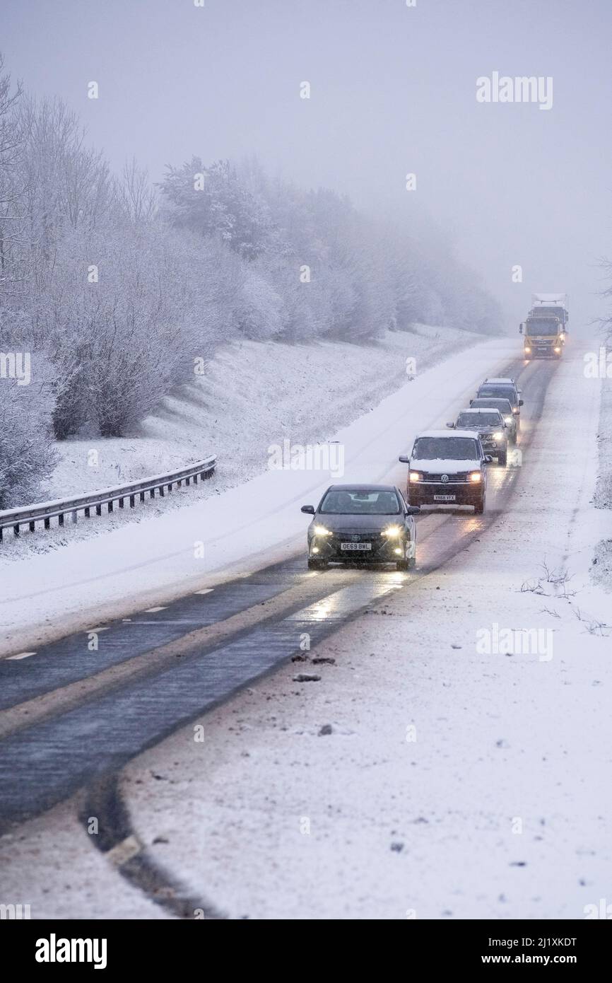 La circulation sur le A417 à l'extérieur de Cirencester fait face à de la neige, des pulvérisations et de la glace pendant la nuit pour des conditions de conduite dangereuses. Banque D'Images