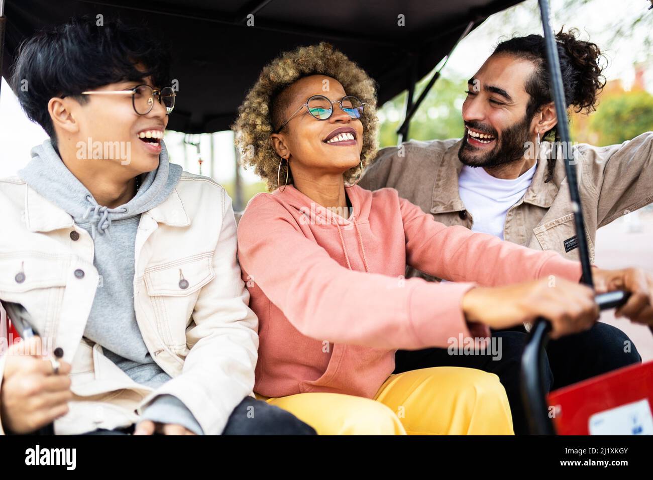 Des amis multiraciaux se embrassant et riant dans la rue de la ville tout en montant un tuk tuk Banque D'Images