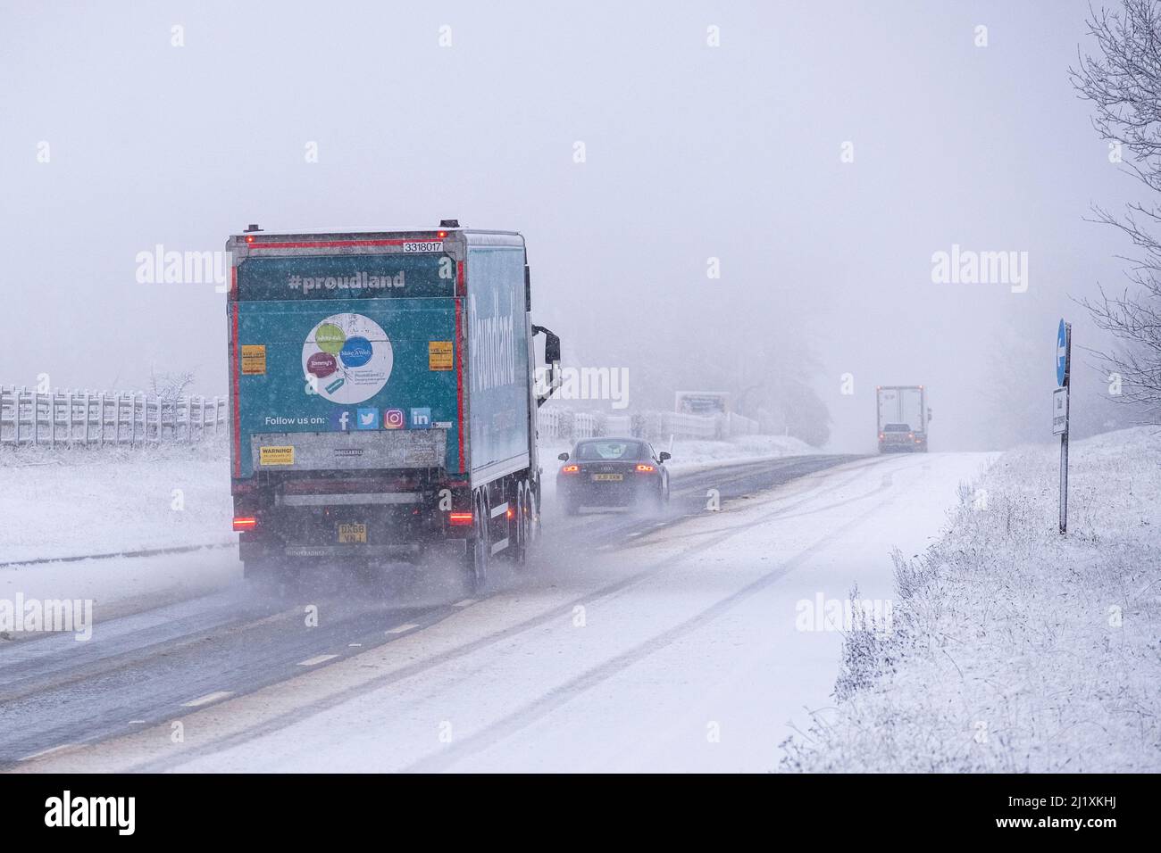 La circulation sur le A417 à l'extérieur de Cirencester fait face à de la neige, des pulvérisations et de la glace pendant la nuit pour des conditions de conduite dangereuses. Banque D'Images