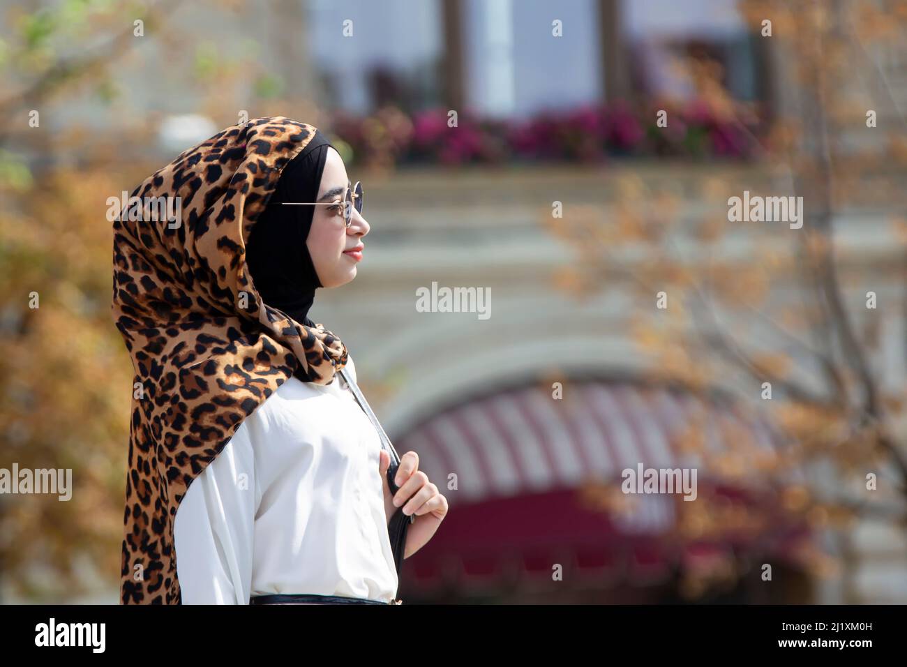 Russie, Moscou, 29 juillet 2018, place Rouge. Une belle fille orientale dans un hijab en profil contre un bâtiment de ville flou. Banque D'Images