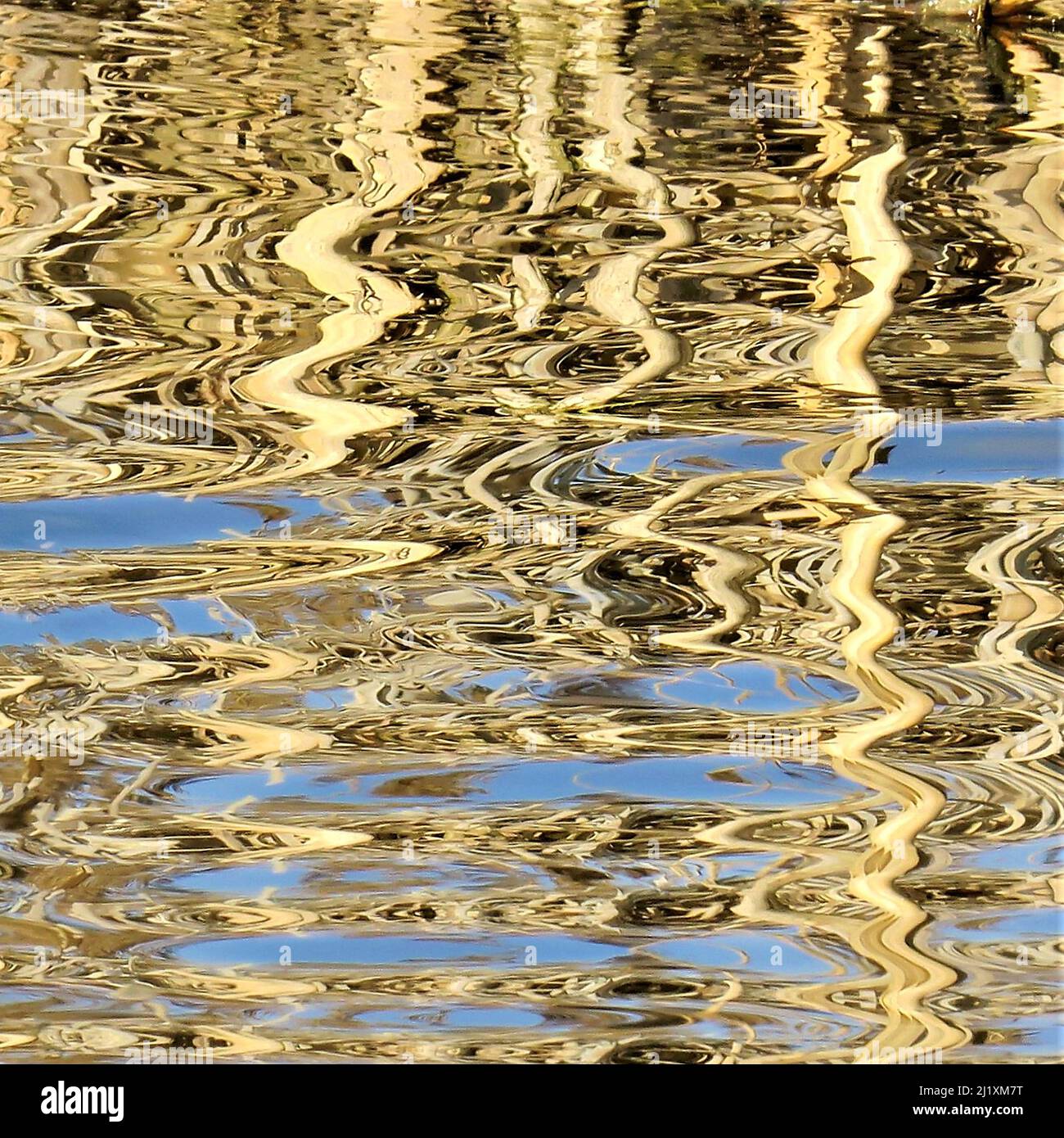 Photographie de la voie navigable abstraite montrant le motif, la texture, la forme et le mouvement réfléchis, avec une pallette bleu et or montrant la lumière forme un mirro Banque D'Images