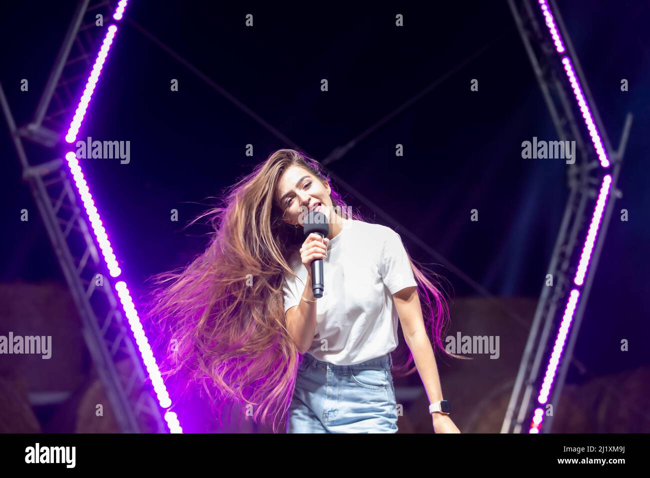 Une fille aux cheveux longs chante sur scène. Banque D'Images