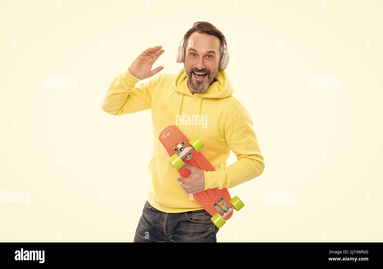 joyeux skateboarder écoutez de la musique dans les écouteurs tenez le skateboard isolé sur blanc, en s'amusant. Banque D'Images