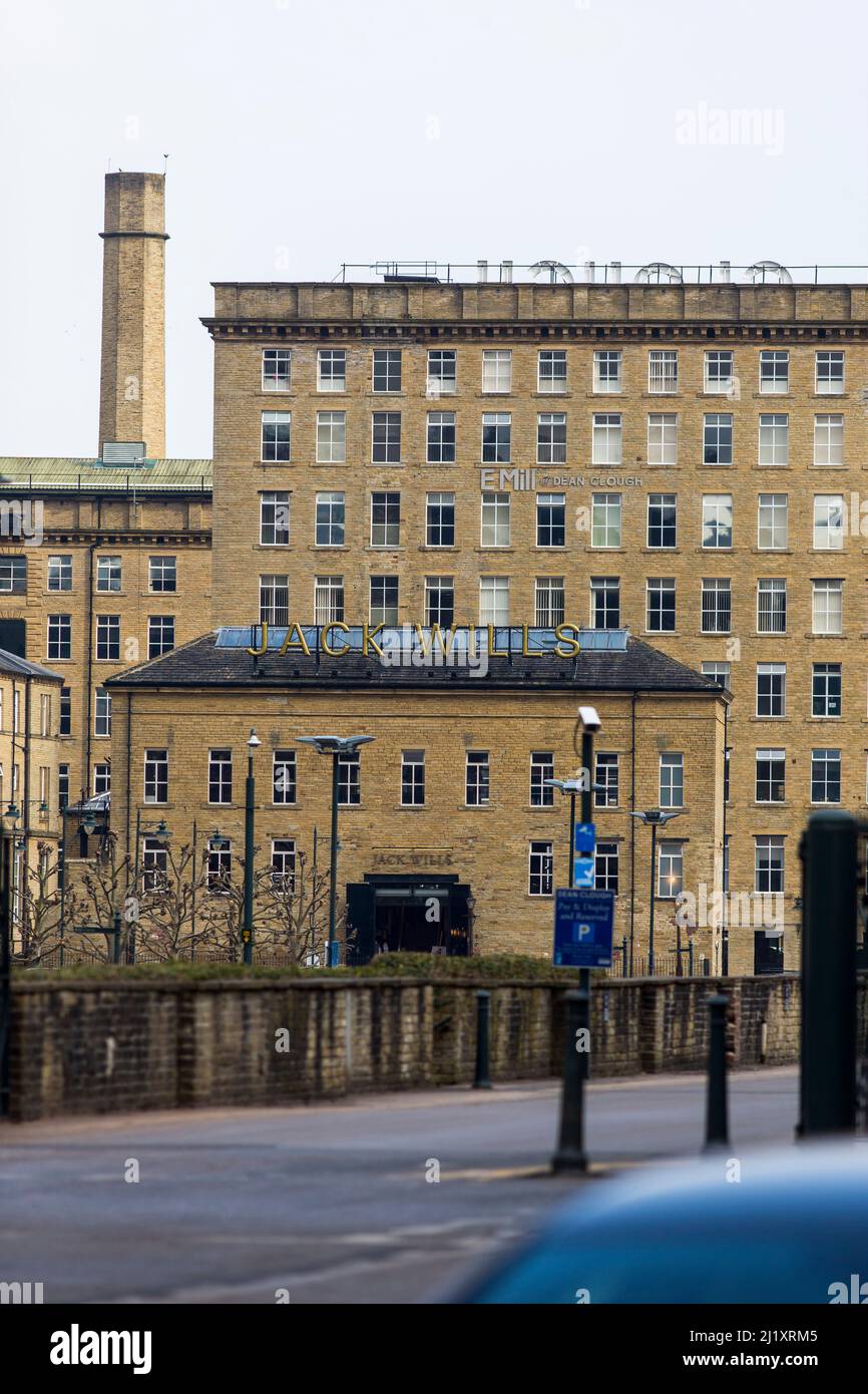 Dean Clough, situé à Halifax, à Calfoot, dans le West Yorkshire, en Angleterre, est un groupe de grands bâtiments d'usine construits en 1840s–60s pour les tapis de Crossley, devenant l'une des plus grandes usines de tapis au monde (un demi-kilomètre de long avec 1 250 000 pieds carrés (116 000 m2) d'espace au sol). Après des années de baisse de production, il a fermé ses portes en 1983, lorsqu'il a été acheté par un consortium dirigé par Sir Ernest Hall qui a développé le site classé Grade II pour diverses utilisations commerciales et culturelles. Elle est maintenant considérée comme un exemple de régénération urbaine réussie.Dean Clough est situé du côté nord de Halifax, près du V. Banque D'Images