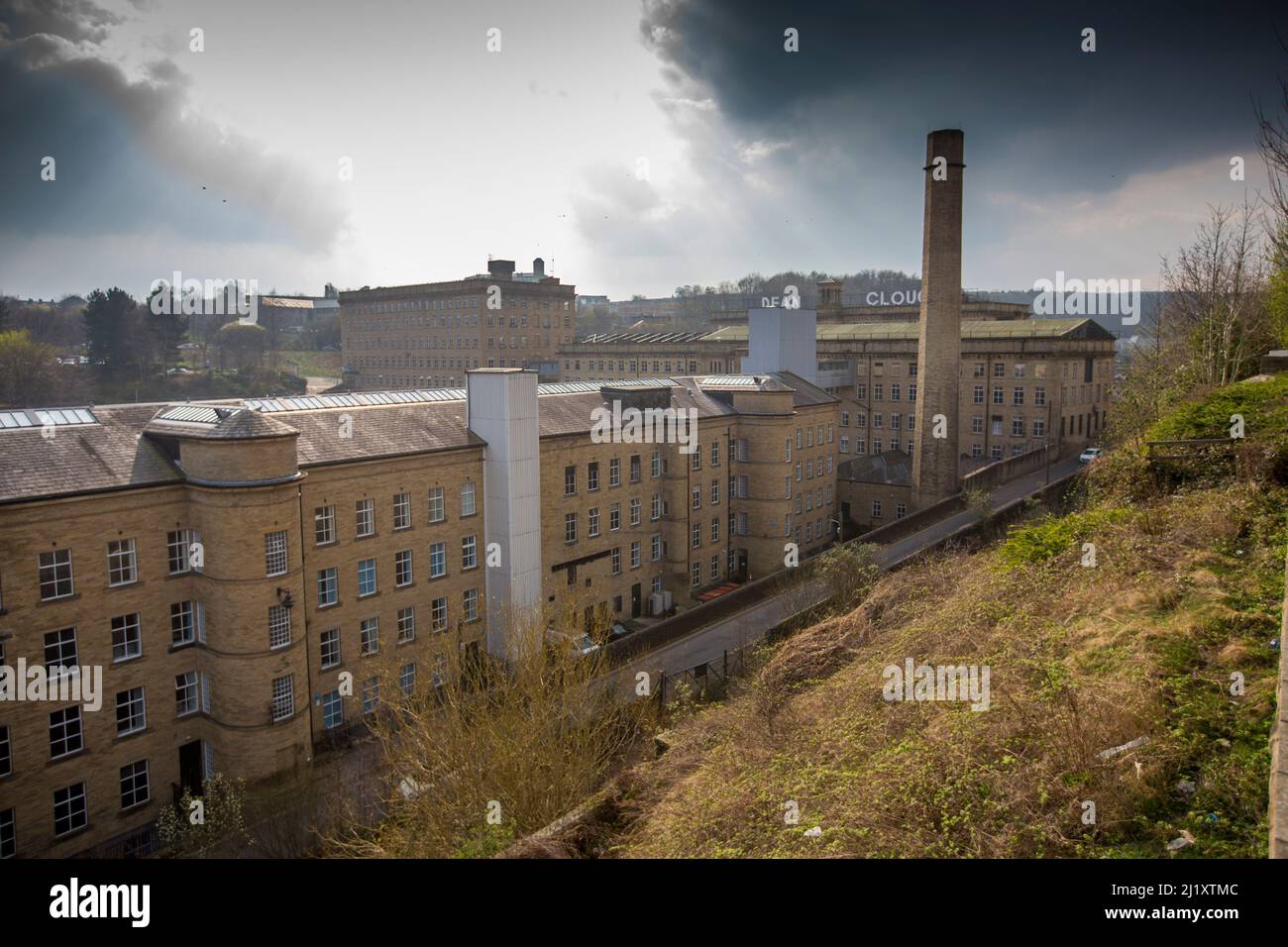 Dean Clough, situé à Halifax, à Calfoot, dans le West Yorkshire, en Angleterre, est un groupe de grands bâtiments d'usine construits en 1840s–60s pour les tapis de Crossley, devenant l'une des plus grandes usines de tapis au monde (un demi-kilomètre de long avec 1 250 000 pieds carrés (116 000 m2) d'espace au sol). Après des années de baisse de production, il a fermé ses portes en 1983, lorsqu'il a été acheté par un consortium dirigé par Sir Ernest Hall qui a développé le site classé Grade II pour diverses utilisations commerciales et culturelles. Elle est maintenant considérée comme un exemple de régénération urbaine réussie.Dean Clough est situé du côté nord de Halifax, près du V. Banque D'Images