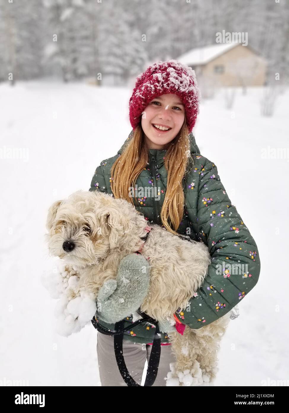 Portrait d'Une jeune fille souriante tenant son chien extrêmement Shaggy dont les griffes sont ancrées dans la neige Banque D'Images