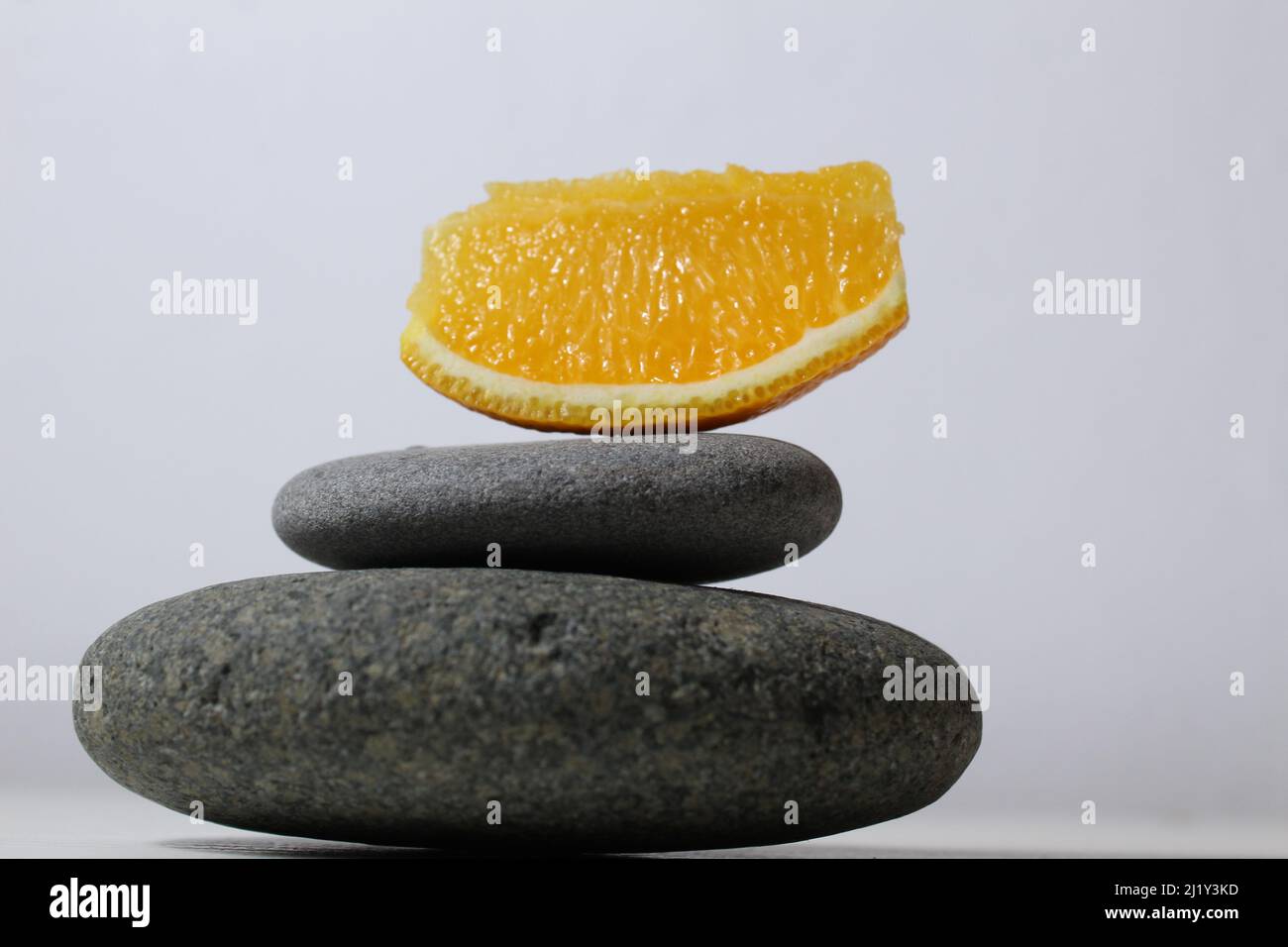 une tour de balans de pierres grises et de fruits orange de pamplemousse sur fond blanc jaune avec de la place pour le texte. Avantages de l'énergie importance de la santé Vitami Banque D'Images