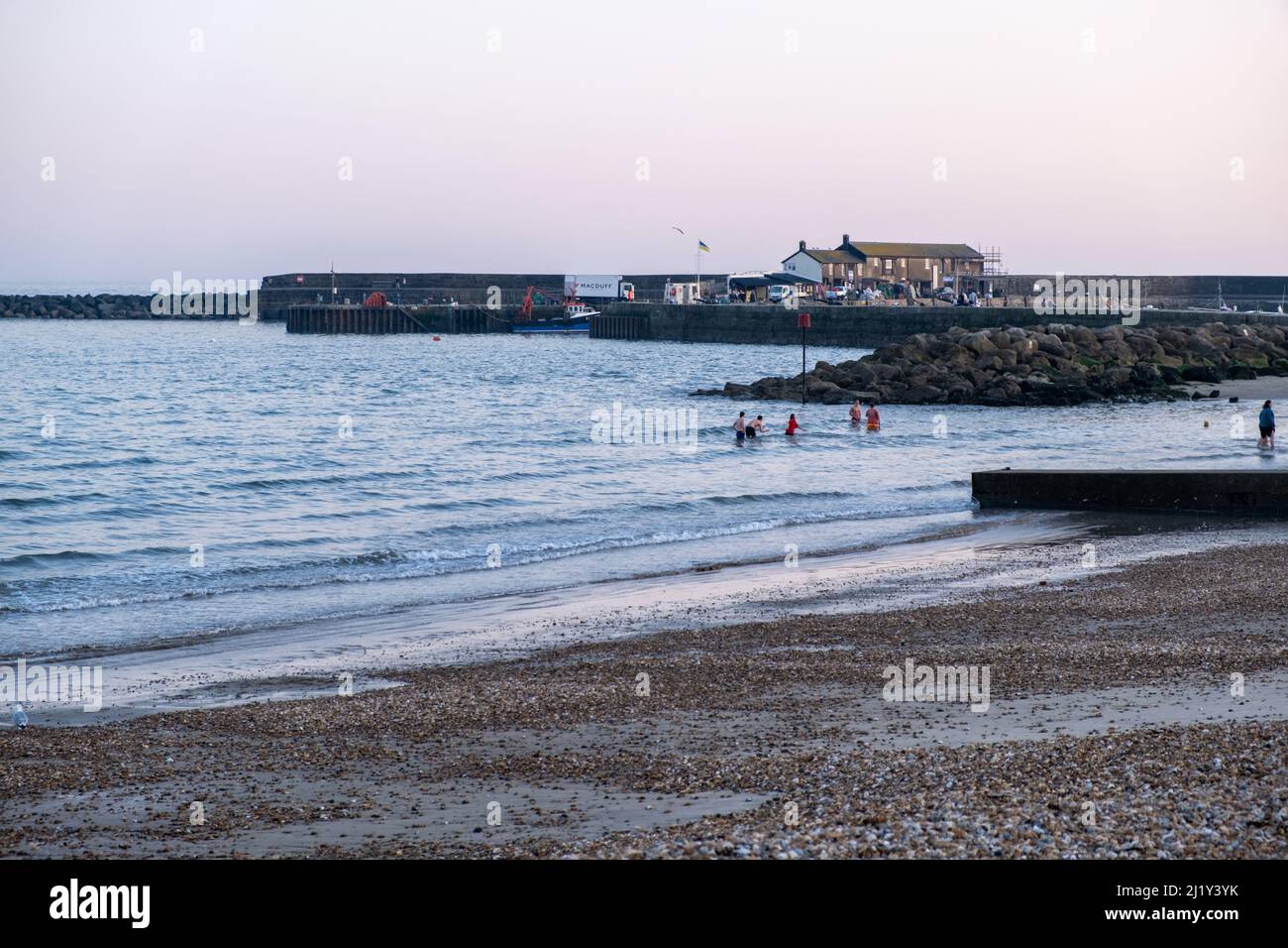 Adolescents jouant dans la sae au crépuscule à Lyme Regis, Royaume-Uni (Mar22) Banque D'Images