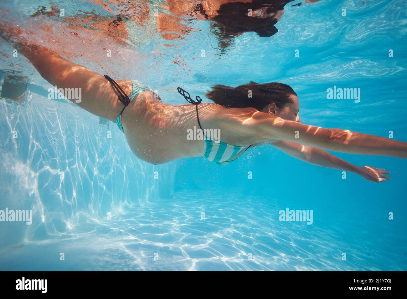 Femme enceinte nageant dans la piscine sous l'eau Banque D'Images