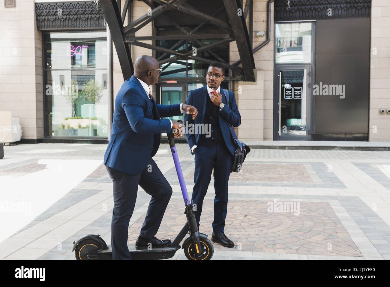 Rencontre de deux partenaires d'homme d'affaires afro-américain noir en costumes et lunettes à l'extérieur dans un bloc de ville. Amitié et partenariat d'affaires Banque D'Images