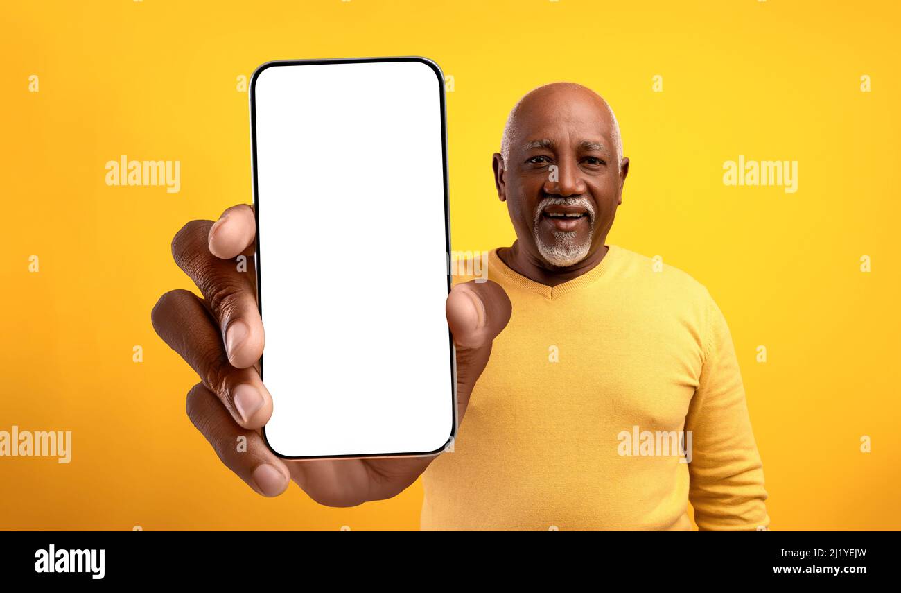 Super application. Homme senior afro-américain montrant un grand écran vide de téléphone portable, recommandant votre annonce, maquette Banque D'Images