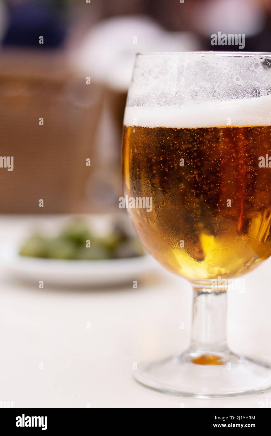bière dans un verre sur une table à l'extérieur avec des olives en arrière-plan Banque D'Images