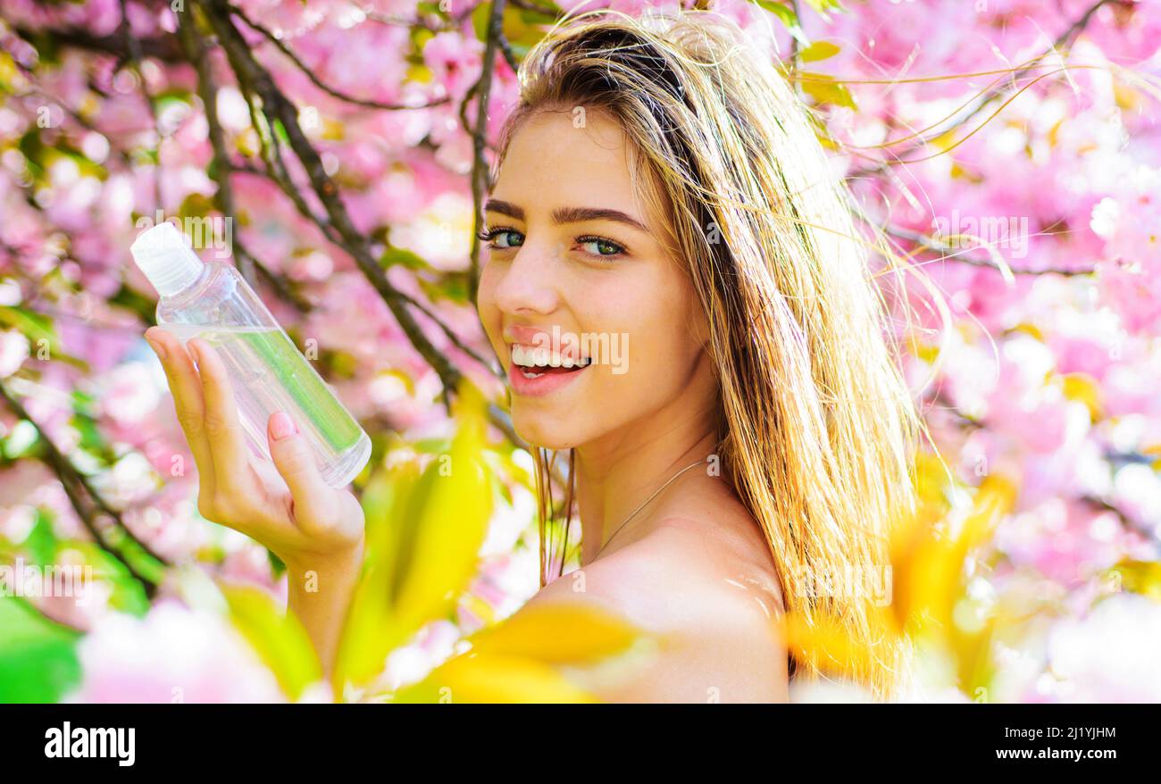 Produits de soin du visage. Fille souriante avec de l'eau micellaire. Cosmétiques pour femmes. Tonique, lotion. Cosmétologie. Banque D'Images