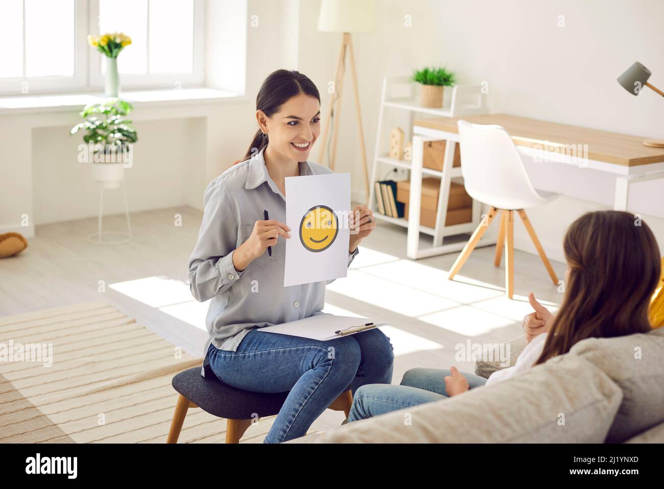 Thérapeute ou psychologue utilisant des images d'emoji tout en parlant à l'enfant des émotions Banque D'Images