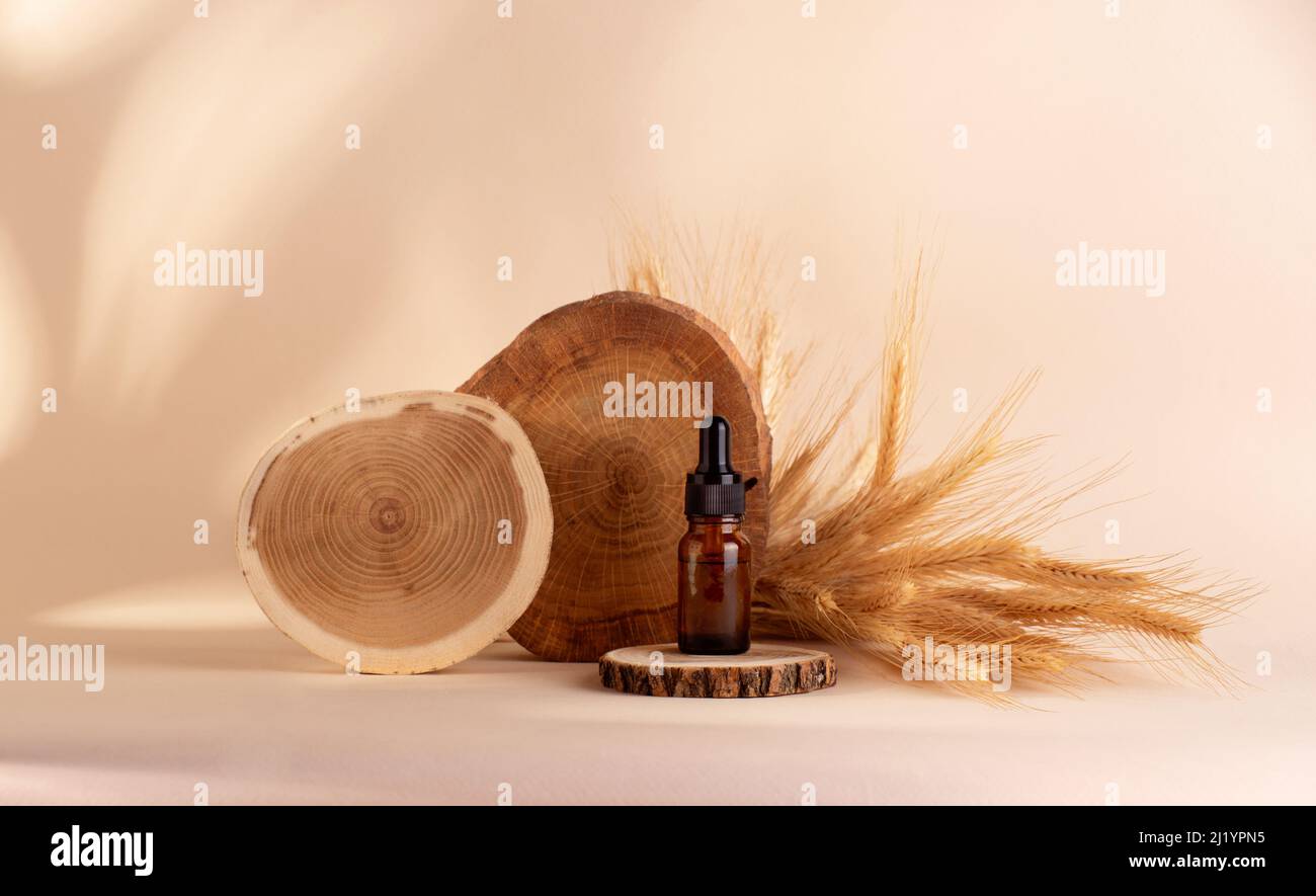 Huile biologique de céréales de seigle et de blé en bouteille avec un compte-gouttes debout sur un podium en bois sur fond beige. Banque D'Images