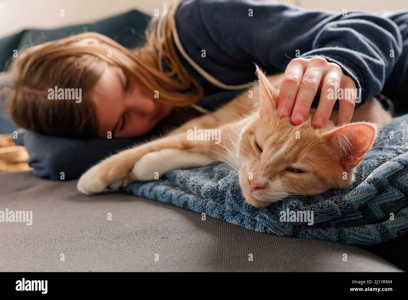 Une jeune adolescente allongé sur un canapé trouve le confort en se blottant près de son chat et en le caressant Banque D'Images