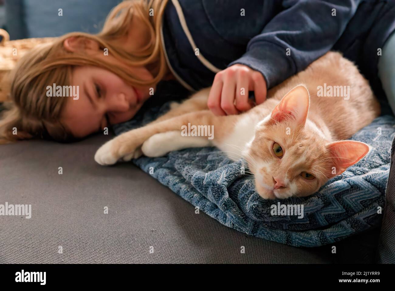 Une jeune adolescente allongé sur un canapé trouve le confort en se blottant près de son chat et en le caressant Banque D'Images