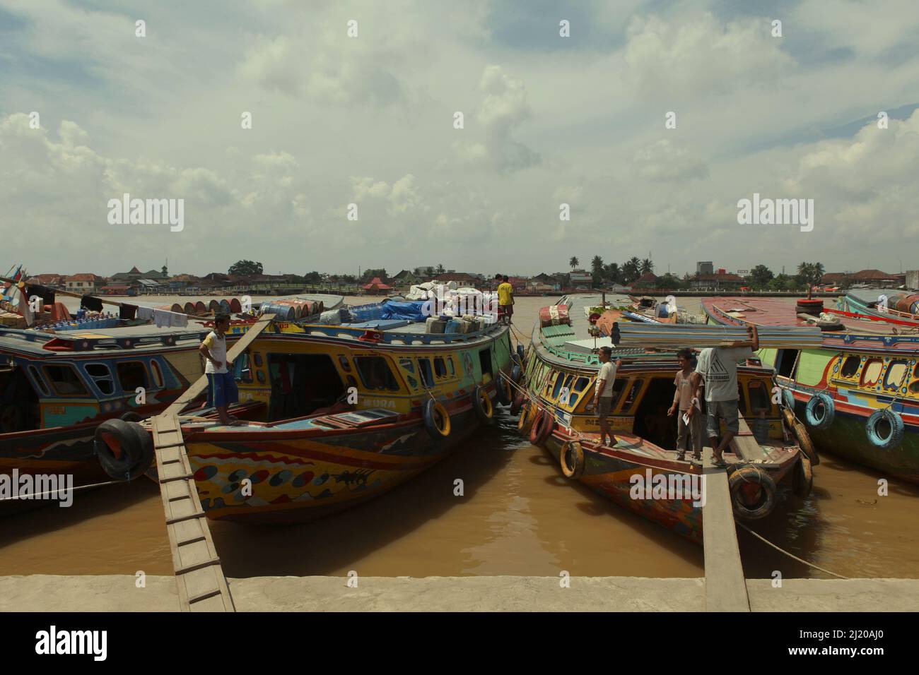 Activités des travailleurs qui se tiennent sur les bateaux en bois qui sont liés à un port sur la rive de la Musi à Palembang, Sumatra Sud, Indonésie. Les nouvelles de 2012 ont révélé qu'il est probable que les gens sont venus de la période Srivijaya-Sailendra ont été parmi la colonie qui vivait déjà à Madagascar depuis 1 200 ans. La conclusion était basée sur une recherche sur l'ADN de la mitrochondrie menée par une équipe dirigée par le biologiste moléculaire Murray Cox de l'Université Massey, en Nouvelle-Zélande. Une simulation informatique a suggéré que la colonisation (de Srivijaya) a commencé vers 830 A.D. Banque D'Images