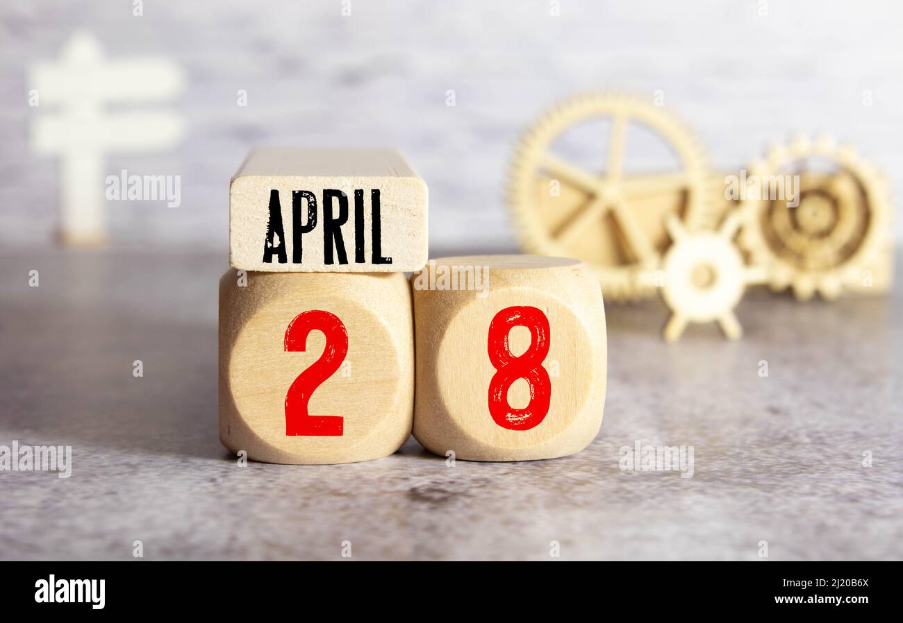 Calendrier pour avril 28 : cubes avec le numéro 28, le nom du mois d'avril en anglais, un bouquet de gouttes de neige en fleurs sur fond jaune dans Banque D'Images