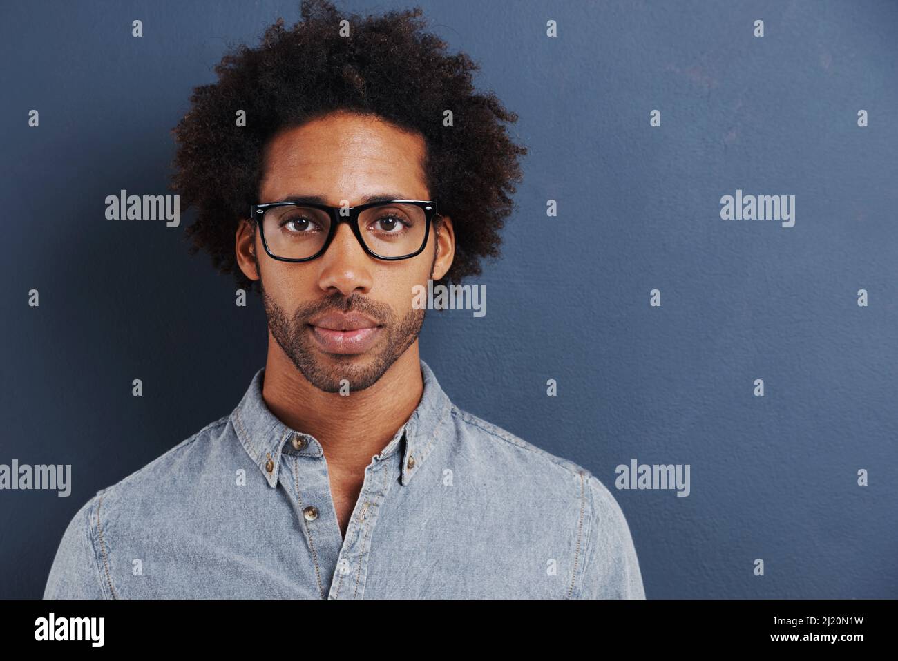 Vous pensez que vous êtes intelligent. Portrait d'un beau jeune homme portant des lunettes sur fond gris. Banque D'Images