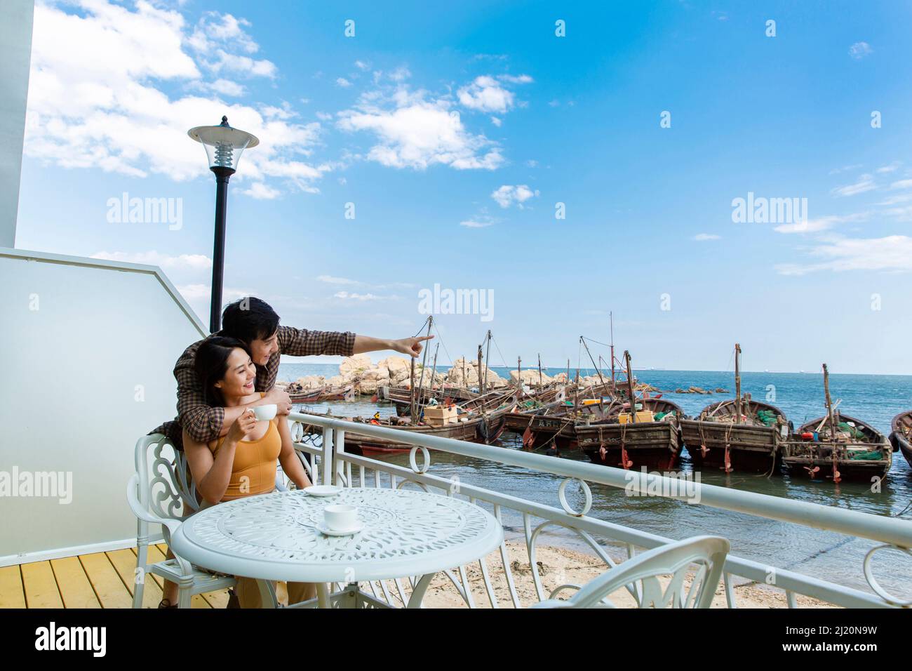 Jeune couple embrassant et prenant la vue au restaurant de bord de mer - photo de stock Banque D'Images