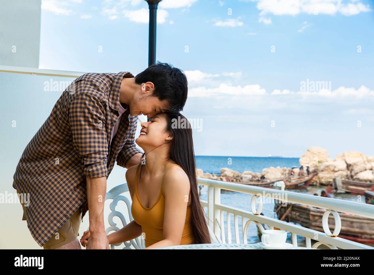 Amoureux qui sont tombés amoureux sur le balcon d'un hôtel de bord de mer - photo de stock Banque D'Images