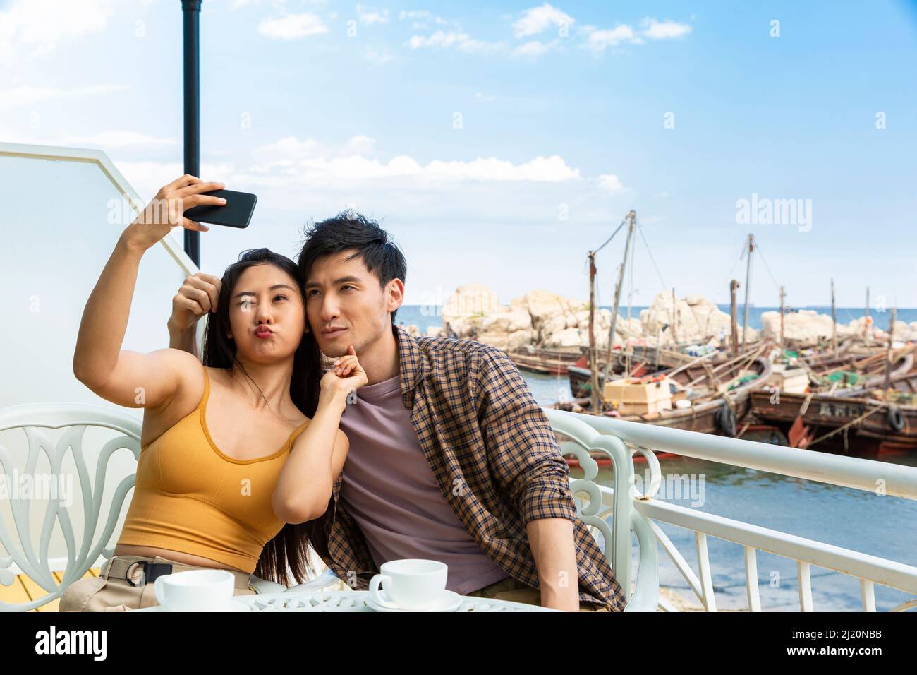 Couples heureux de prendre des selfies dans un café de bord de mer - photo de stock Banque D'Images