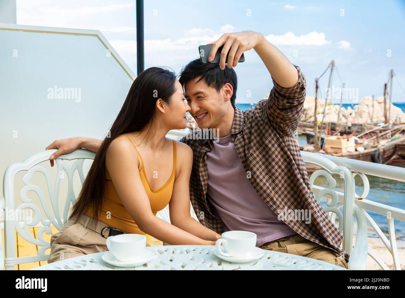 Couples heureux de prendre des selfies dans un café de bord de mer - photo de stock Banque D'Images
