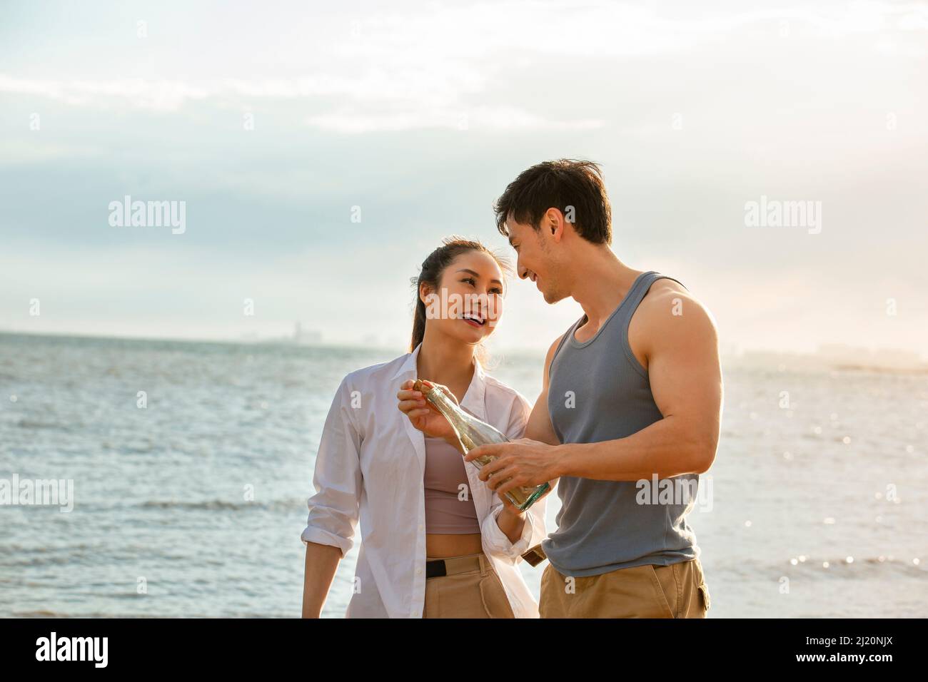 Jeune couple remplissant le message dans la bouteille de dérive sur la plage d'été - photo de stock Banque D'Images