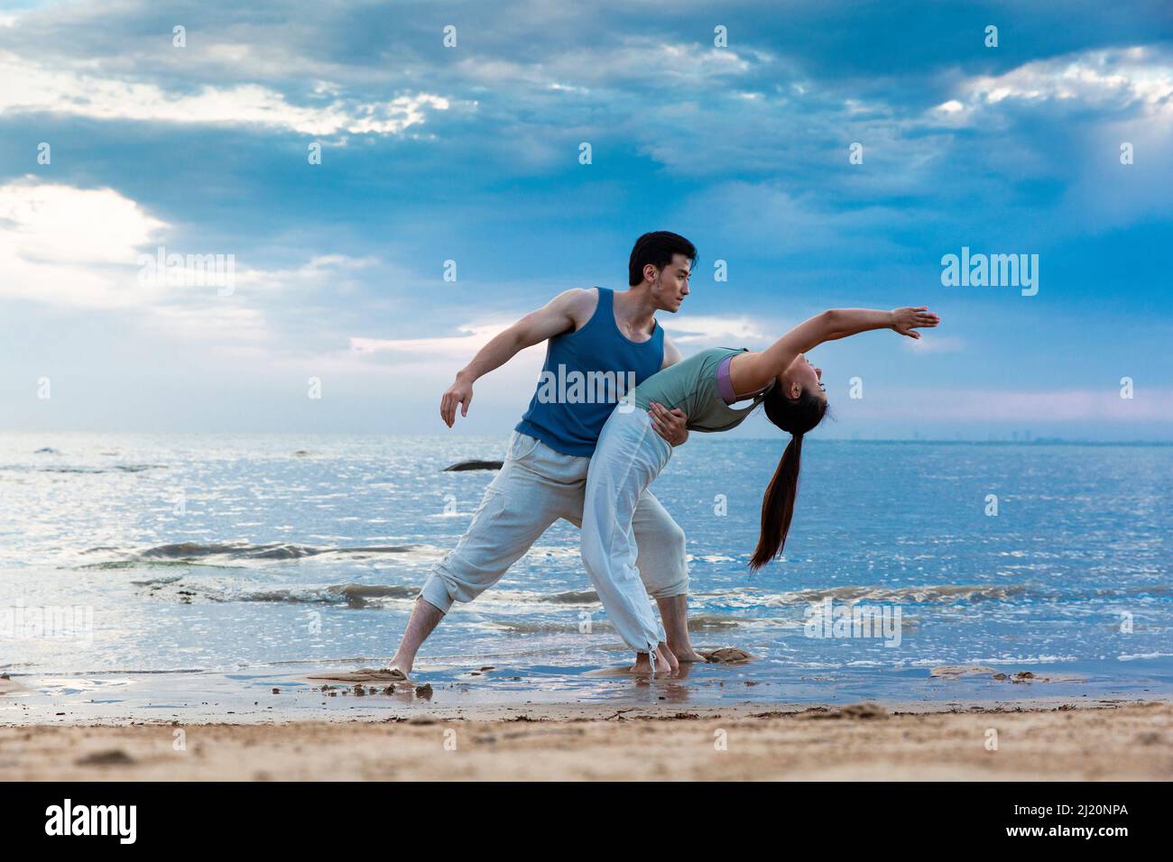 Jeune couple s'étendant sous les magnifiques nuages de bord de mer - photo de stock Banque D'Images