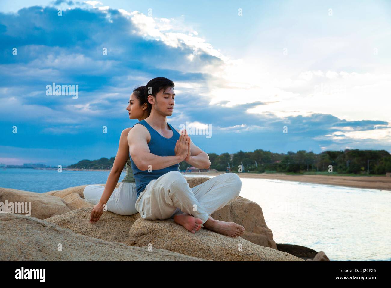 Couples pratiquant le yoga pleine conscience sur les rochers de l'île - photo de stock Banque D'Images