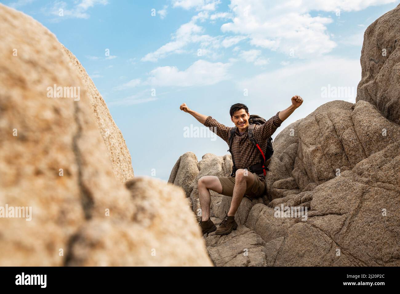 Un jeune routard qui applaudit avec des bras étirés sur des pics rocheux - photo de stock Banque D'Images