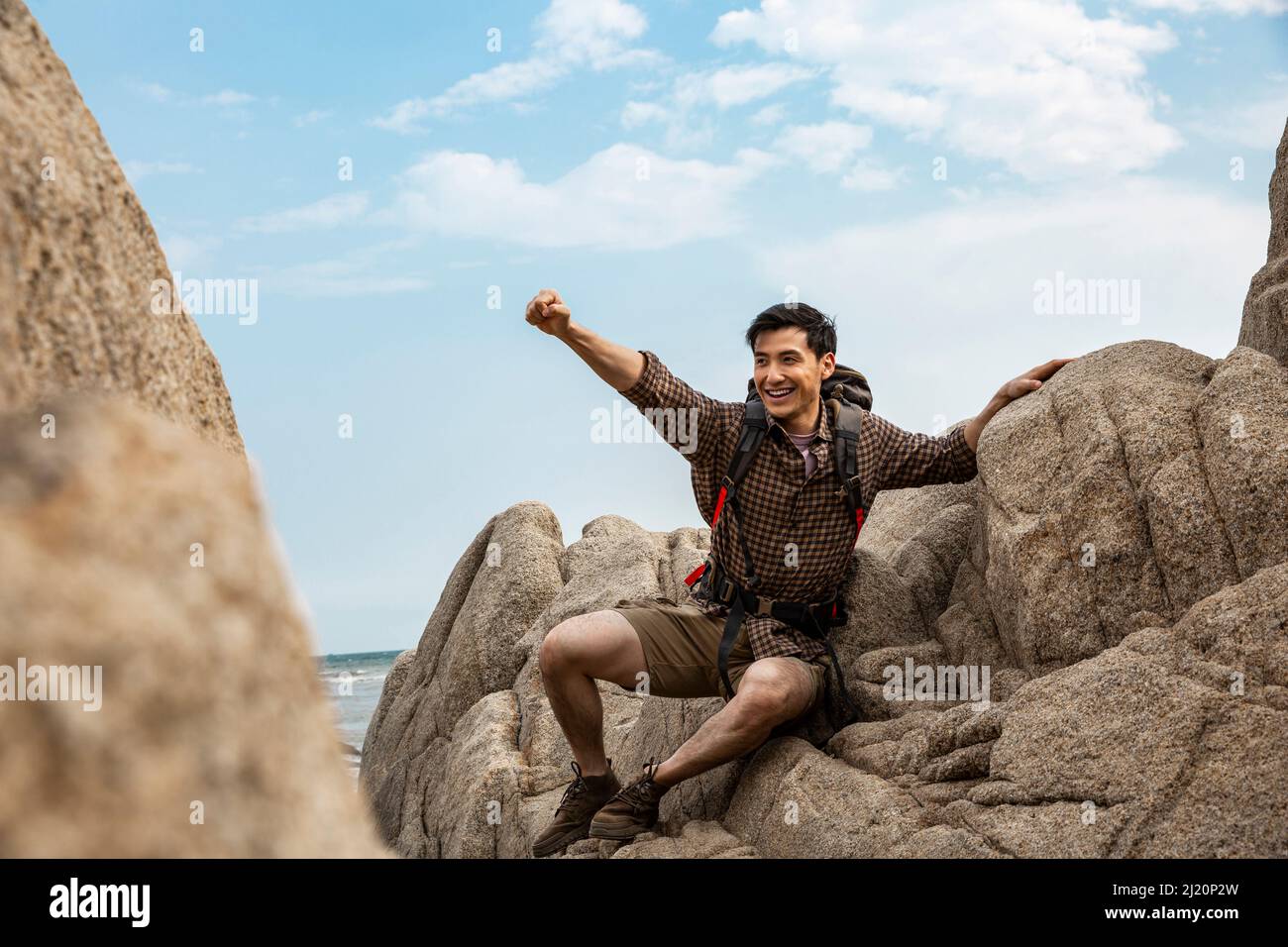 Encourager un jeune routard avec des bras étirés sur les rochers de la plage - photo de stock Banque D'Images