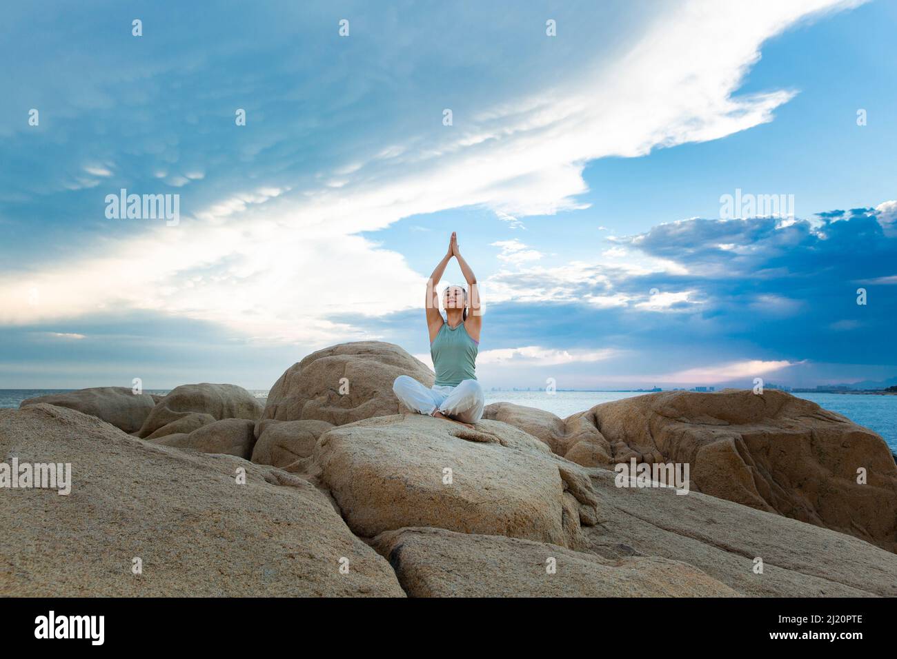 Belle jeune femme pratiquant le yoga sur le récif de la plage - photo de stock Banque D'Images