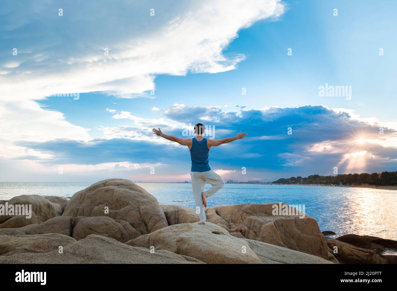 Jeune homme musclé faisant du yoga sur un rocher de plage - photo de stock Banque D'Images