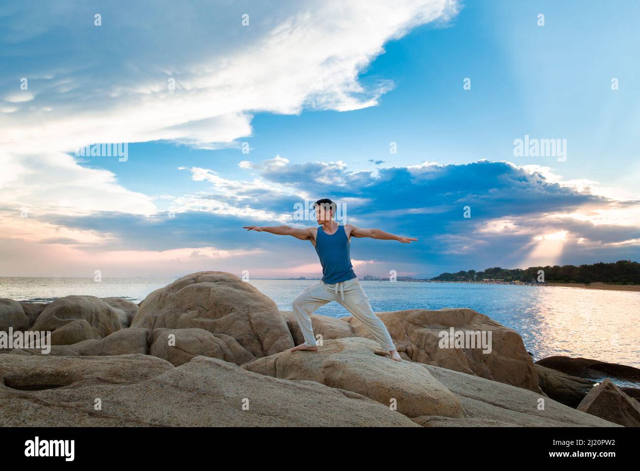 Jeune homme musclé faisant du yoga sur un rocher de plage - photo de stock Banque D'Images