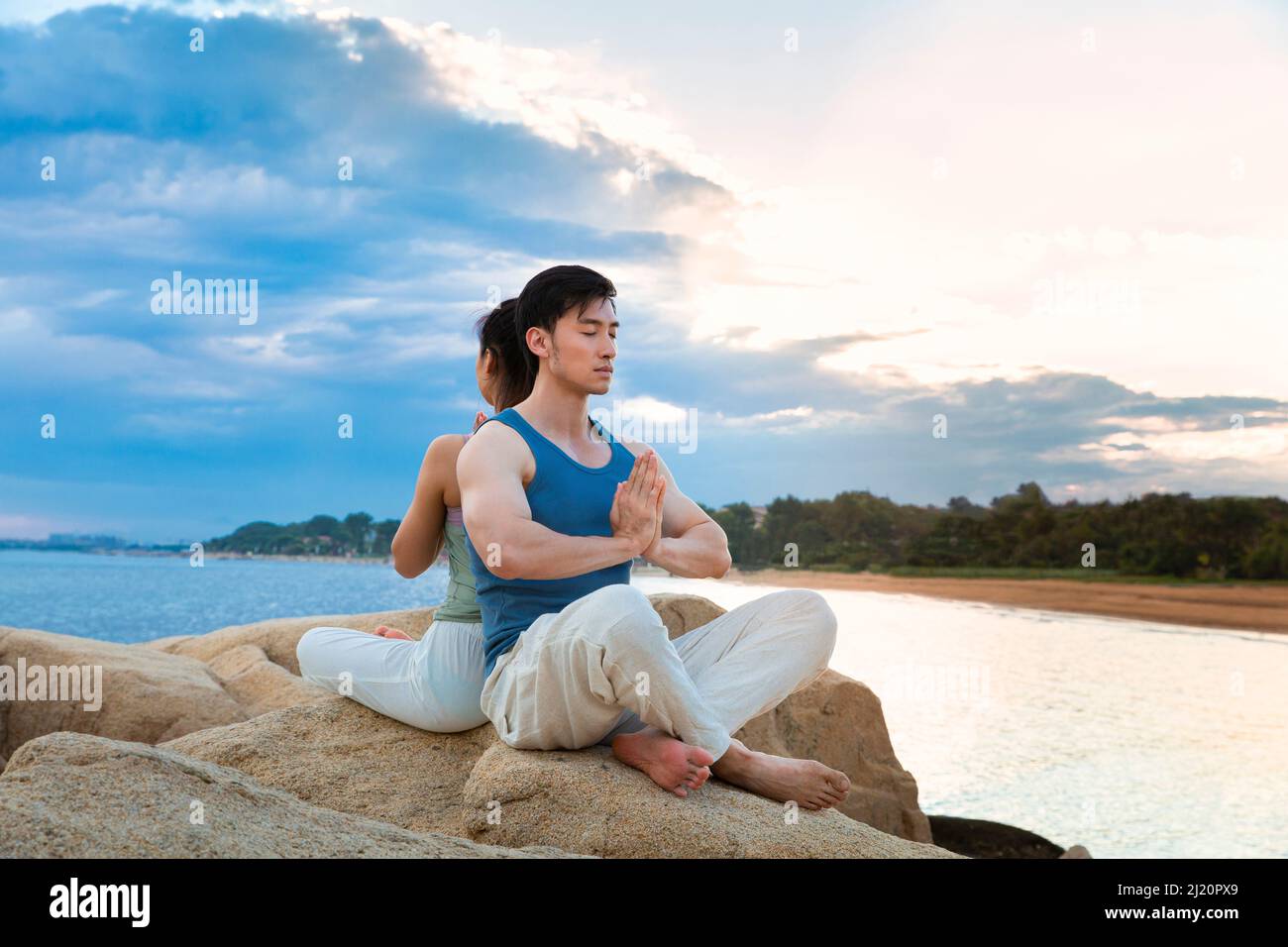 Couples pratiquant le yoga pleine conscience sur les rochers de l'île - photo de stock Banque D'Images