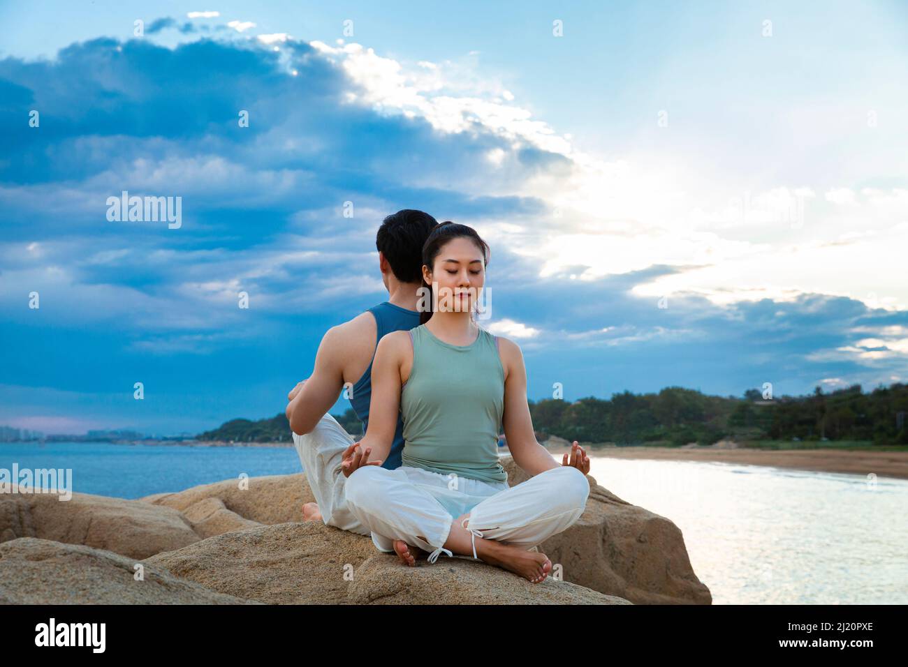 Couples pratiquant le yoga pleine conscience sur les rochers de l'île - photo de stock Banque D'Images