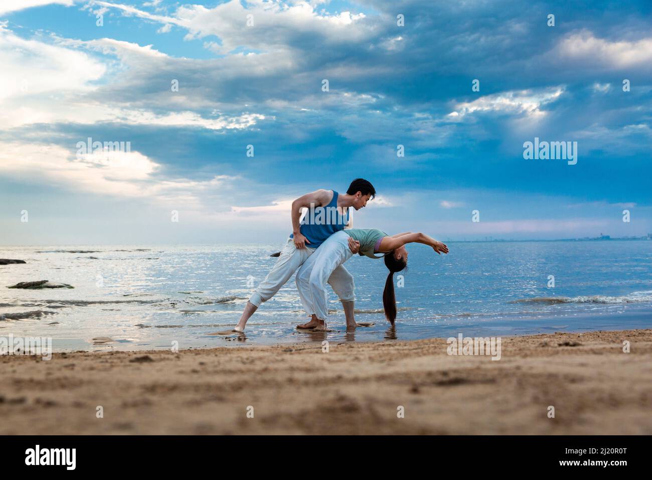 Jeune couple s'étendant sous les magnifiques nuages de bord de mer - photo de stock Banque D'Images