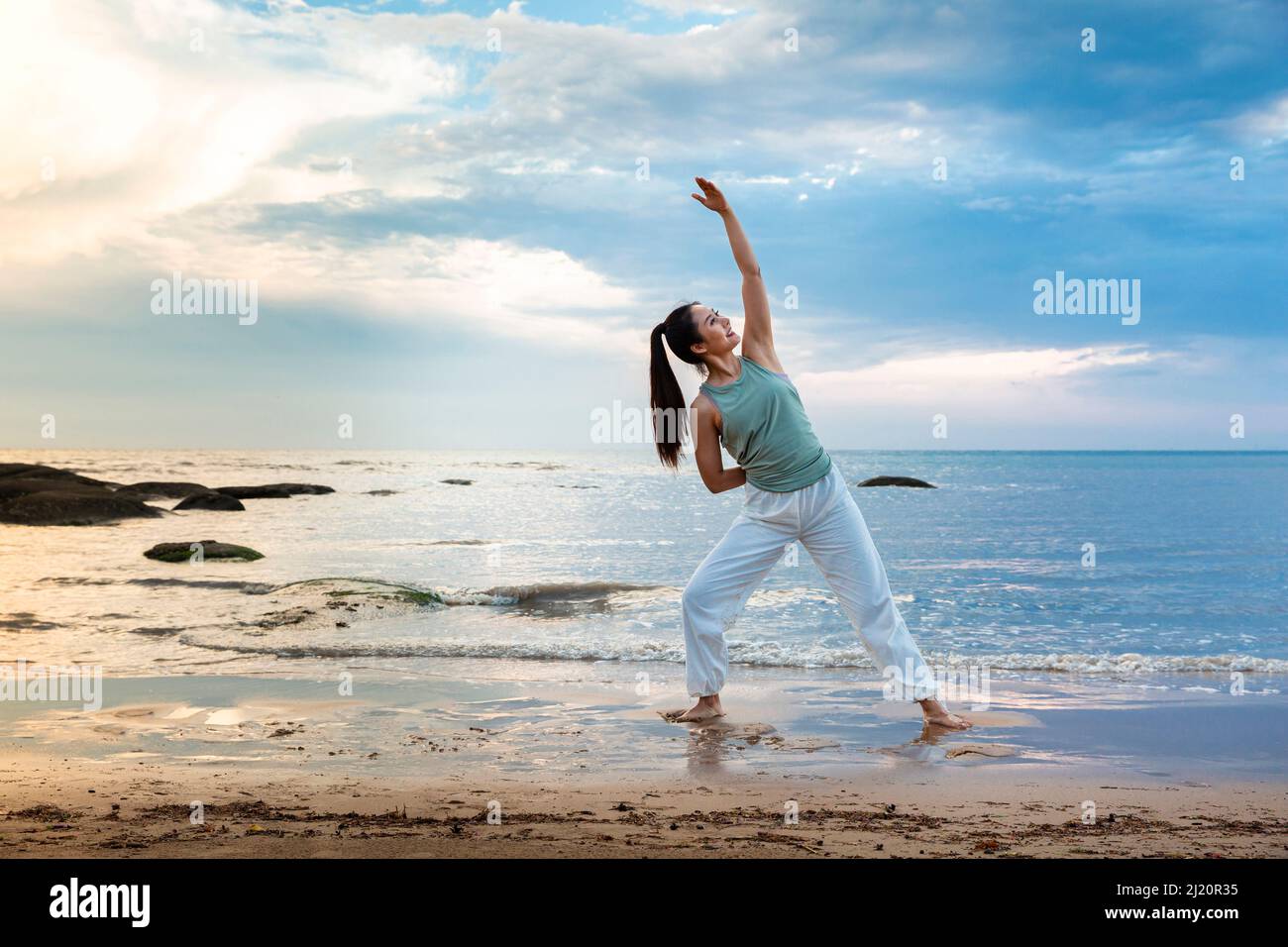Jeune femme pratiquant le yoga seul sur une plage d'été - photo de stock Banque D'Images