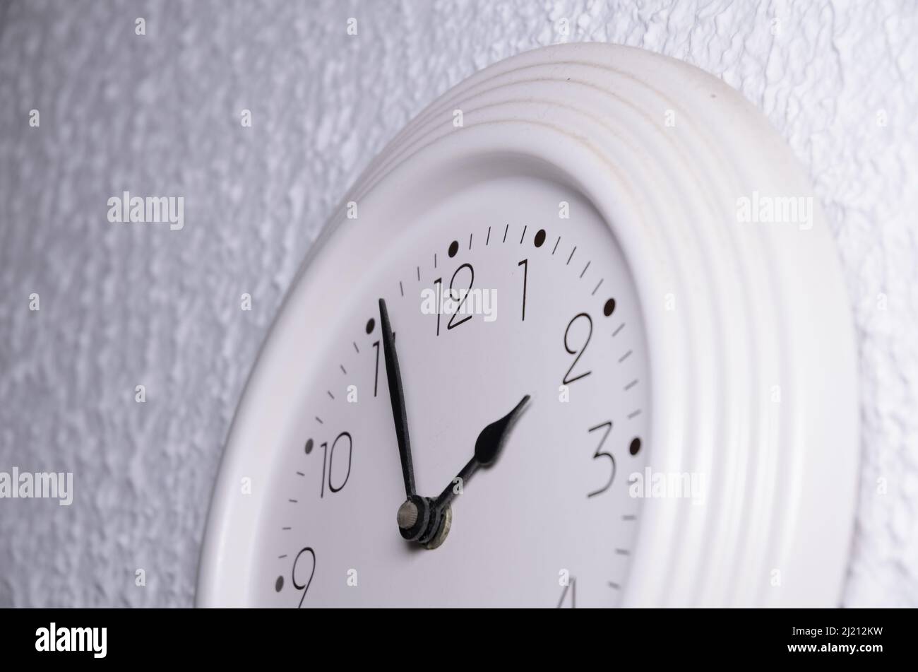 Horloge blanche avec mains noires sur un mur à l'intérieur Banque D'Images