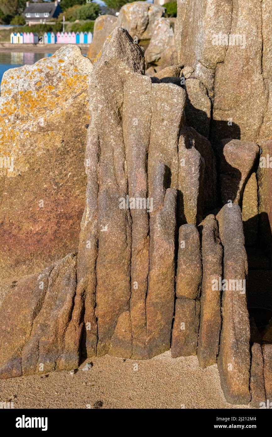 Granit en pierre sur une plage en Bretagne, ile-aux-Moines, avec cabines de bain en arrière-plan Banque D'Images