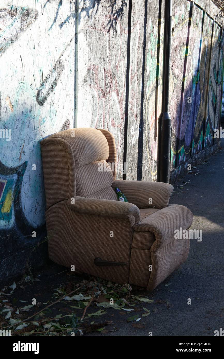 Un fauteuil laissé à côté d'un mur couvert de graffiti à Sheffield, au Royaume-Uni Banque D'Images