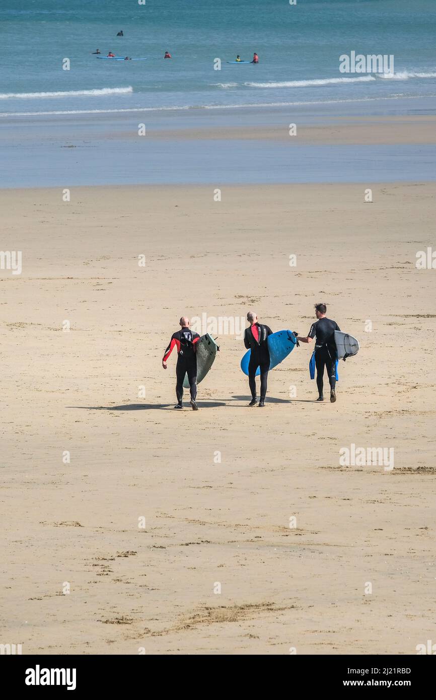 Surfeurs transportant leurs planches de surf marchant jusqu'à la mer sur Towan Beach à Newquay, en Cornouailles, au Royaume-Uni. Banque D'Images