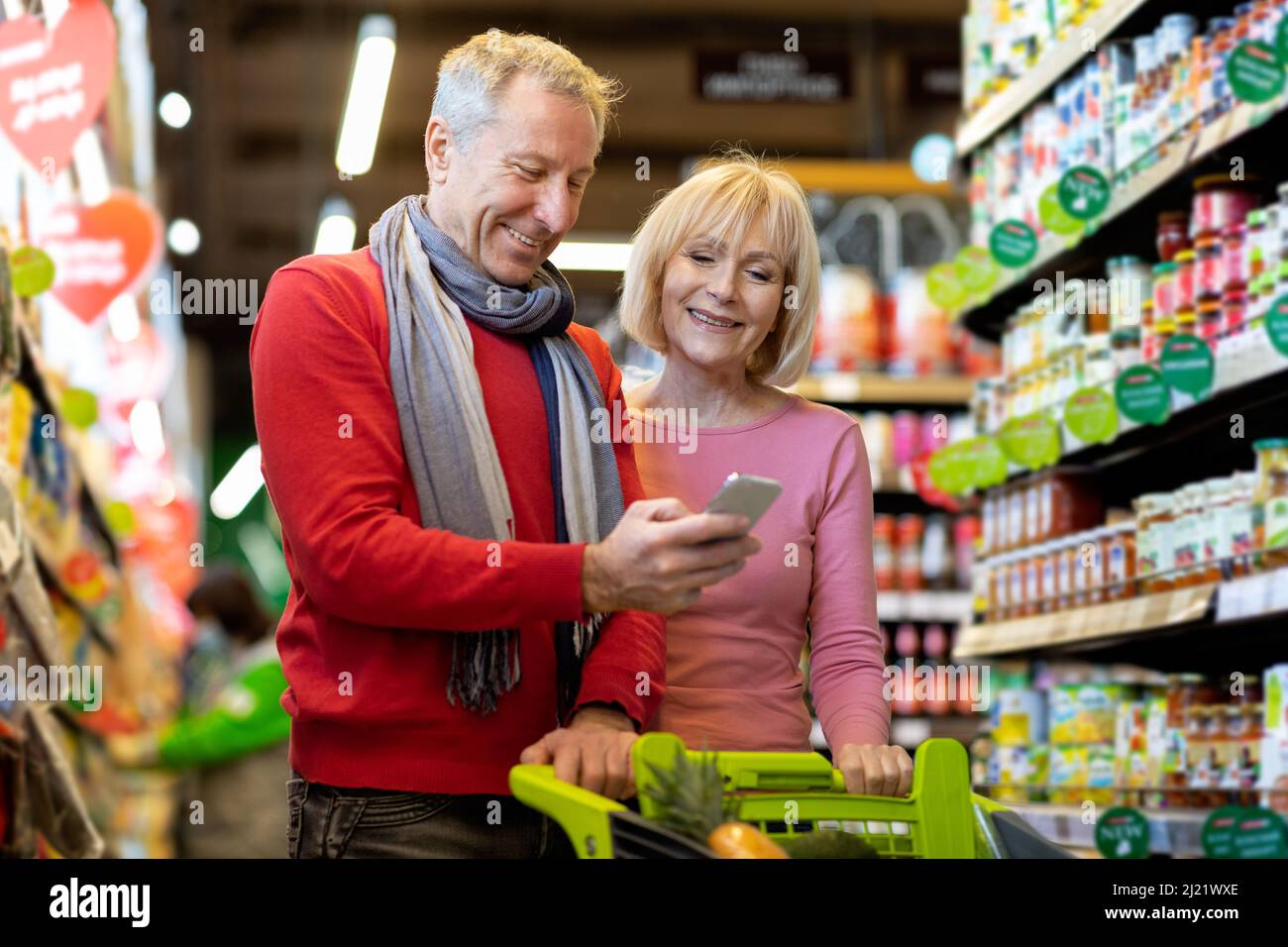 Sourire clients couple senior faisant l'épicerie dans le supermarché Banque D'Images