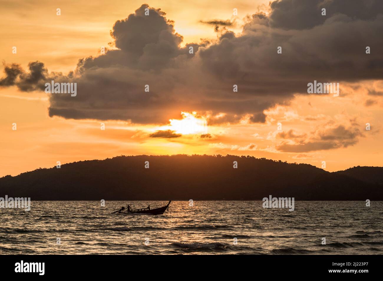 Coucher de soleil sur une terre boisée avec océan en premier plan. Banque D'Images