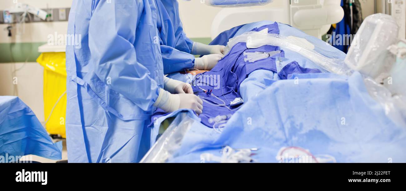 Deux médecins chirurgiens non-descript effectuant une chirurgie dans une salle chirurgicale portant des exfoliants bleus et des gants en latex blanc Banque D'Images